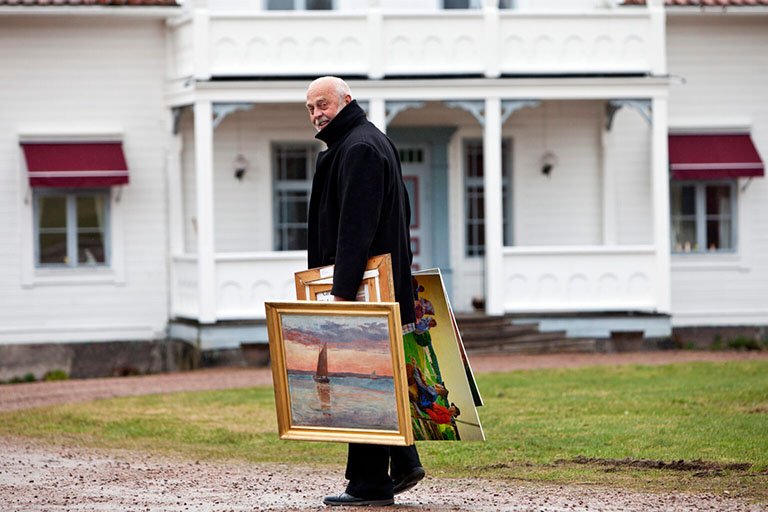 Konstguide bär på tavlor på gårdsplanen